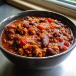 Close-up of a hearty bowl of high protein chili, rich with ground meat and kidney beans in a thick tomato sauce.