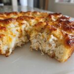 A close-up view of a section cut from the chicken bubble biscuit bake casserole, showing shredded chicken filling and melted cheese.