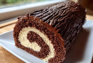 Close-up of a chocolate yule log cake showing the swirl of dark cake and light cream filling.