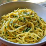 Close-up of creamy lemon pasta tossed with fresh parsley in a white bowl.
