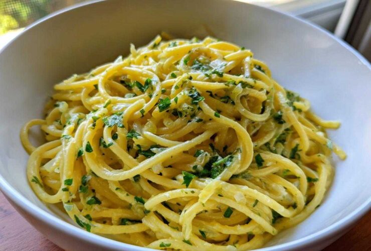 Close-up of creamy lemon pasta tossed with fresh parsley in a white bowl.