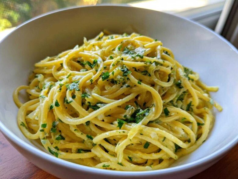 Close-up of creamy lemon pasta tossed with fresh parsley in a white bowl.