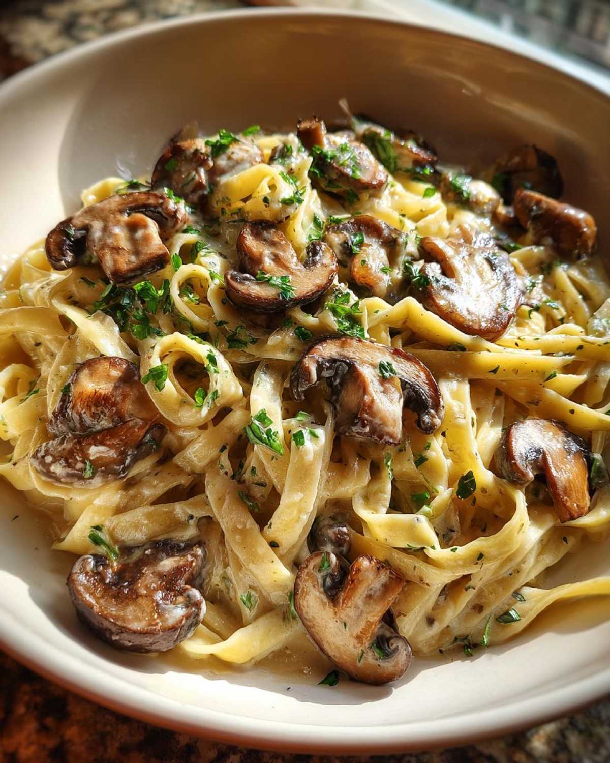 Close-up of creamy fettuccine mushroom pasta topped with sautéed mushrooms and fresh parsley.