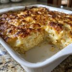 Close-up of creamy baked scalloped potatoes in a white dish with a deeply browned, cheesy crust.