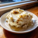 A serving of fluffy slow cooker mashed potatoes topped with melted butter and crispy bits.