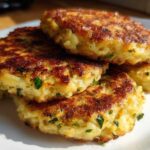 A stack of four golden brown, pan-fried mashed potato cakes seasoned with green herbs.