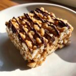 Close-up of a gooey peanut butter rice krispie treats square drizzled with dark chocolate.