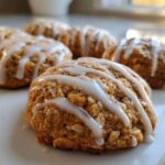 Close-up of soft, gooey persimmon cookies drizzled with white vanilla glaze on a white platter.