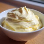 A close-up of freshly made, thick, and creamy homemade mayonnaise piled high in a small white bowl.