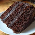Close-up of a rich, dark slice of chocolate cake recipe with moist crumb and frosting.