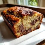Close-up of a moist slice of chocolate chip banana bread showing melted chocolate chunks inside.