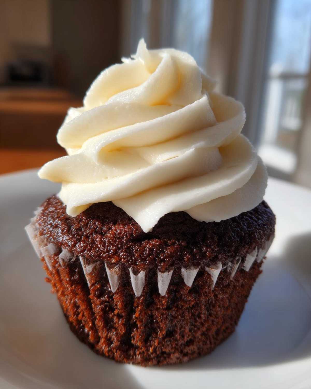A single, moist gingerbread cupcake topped with a generous swirl of white cream cheese frosting.
