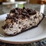 A close-up view of a thick slice of no-bake oreo pie with a creamy filling and dark cookie crust.