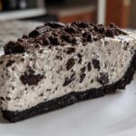 A thick slice of creamy no-bake oreo pie with a dark chocolate crust and topped with crushed oreos.