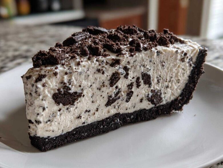 A thick slice of creamy no-bake oreo pie with a dark chocolate crust and topped with crushed oreos.