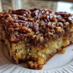 Close-up of a moist slice of pecan upside down cake showing the sticky, caramelized pecan topping and fluffy cake base.