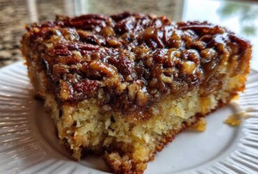 Close-up of a moist slice of pecan upside down cake showing the sticky, caramelized pecan topping and fluffy cake base.