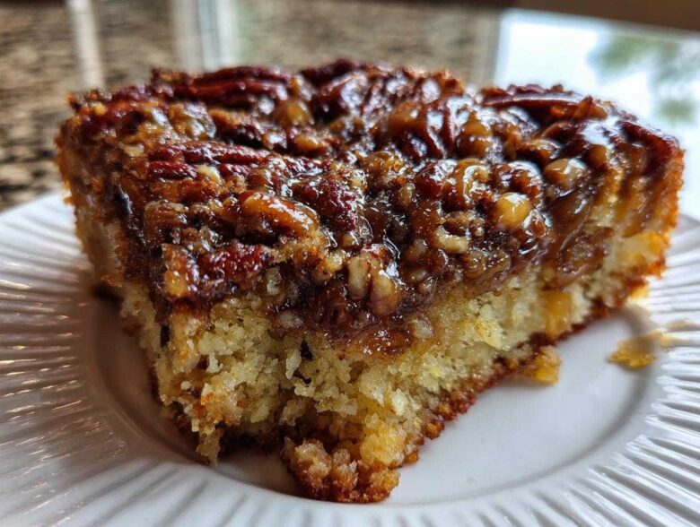 Close-up of a moist slice of pecan upside down cake showing the sticky, caramelized pecan topping and fluffy cake base.
