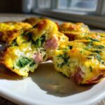 A savory egg muffin, cut in half to show ham and spinach filling, ready for meal prep.