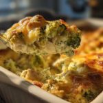 A spoonful of creamy Chicken Divan casserole, featuring broccoli florets and melted, browned cheese topping.