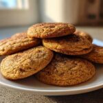 A stack of soft, golden applesauce cookies dusted with cinnamon sugar on a white plate.