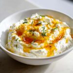 Close-up of creamy whipped ricotta dip with hot honey drizzled on top, garnished with rosemary.