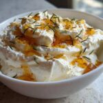 A close-up of creamy whipped ricotta dip with hot honey drizzled on top and garnished with fresh rosemary.