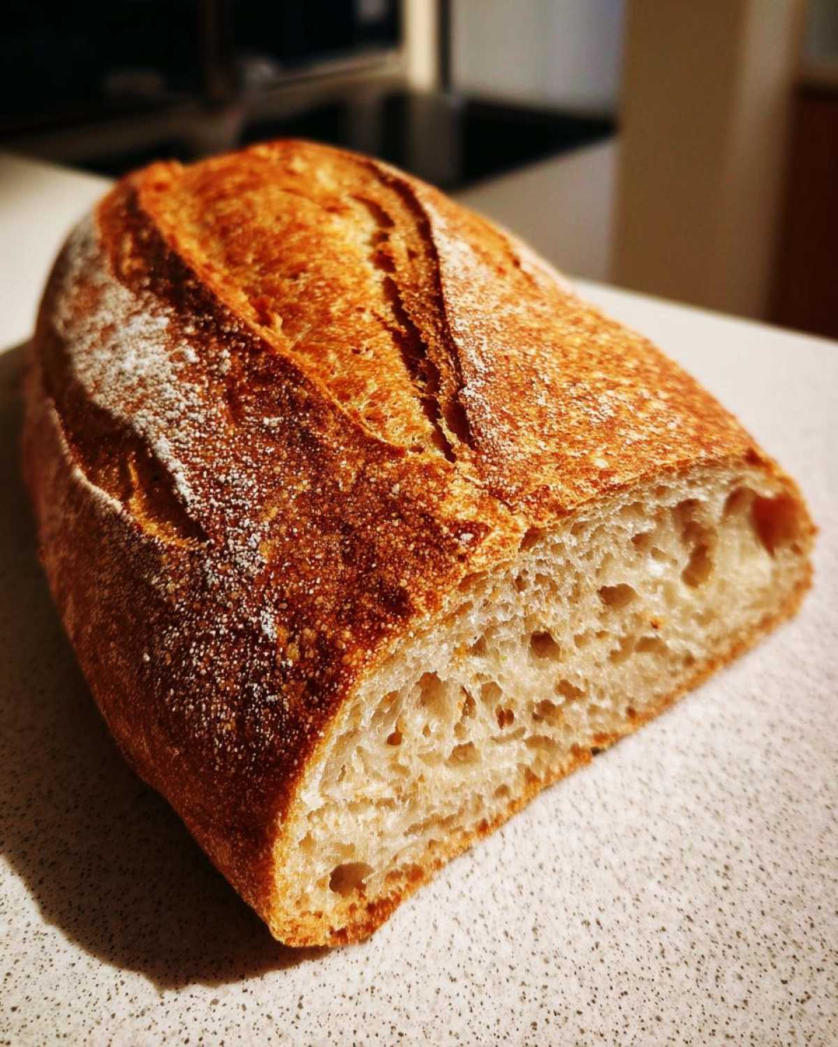 Close-up of a freshly baked french bread loaf cut in half, showing a golden crust and airy interior crumb.