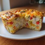 Cross-section view of a hearty egg bake slice showing chunks of chicken, colorful peppers, and a cheesy, browned top.