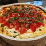 Close-up of a hot, baked 3-cheese bruschetta dip topped with fresh diced tomatoes and basil.