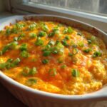 Close-up of a hot, bubbly Buffalo chicken dip topped with melted cheddar cheese and fresh green onions.