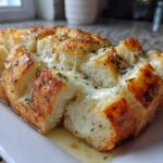 Close-up of a baked, pull-apart style cheese bread loaf with melted mozzarella and herbs.