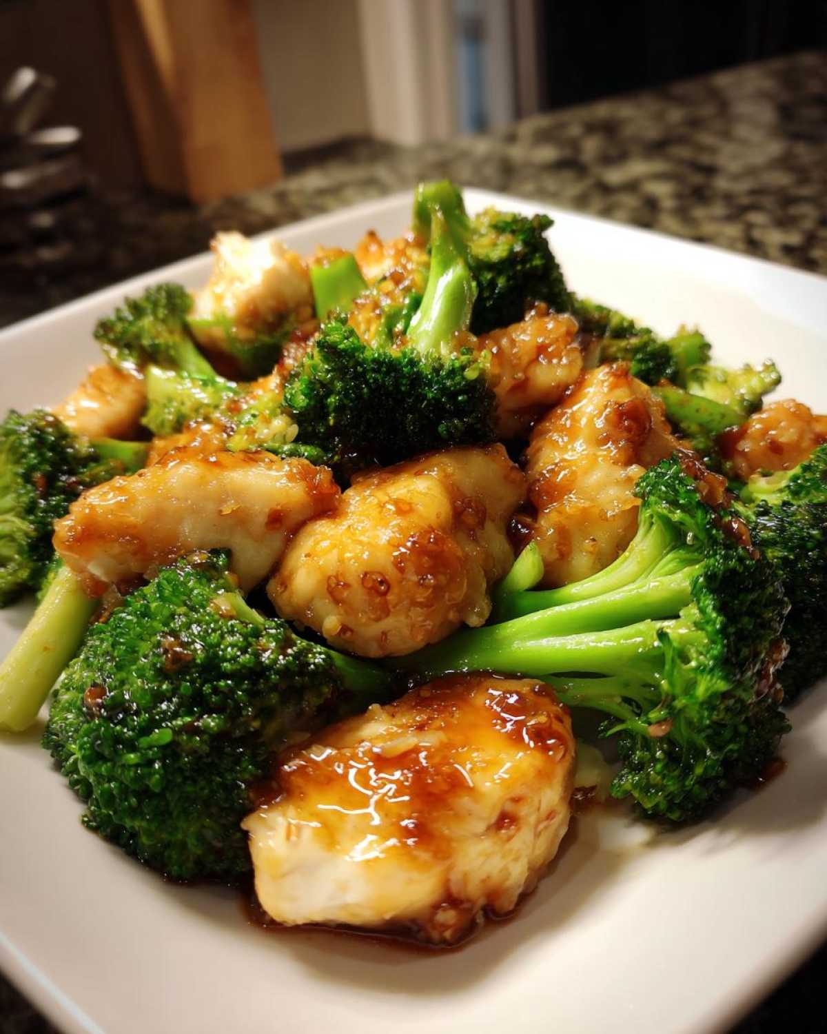 Close-up of tender chicken pieces coated in a savory glaze mixed with bright green broccoli florets, showcasing the chicken and broccoli dish.