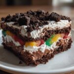 A decadent slice of dirt cake featuring chocolate layers, creamy filling, and a colorful layer of gummy candies.