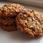 Close-up of a stack of freshly baked, chewy oatmeal cookie treats featuring visible oats and chocolate chips.