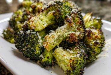 Close-up of crispy, charred roasted broccoli florets topped generously with grated Parmesan cheese.