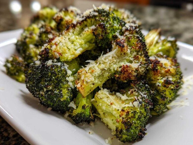 Close-up of crispy, charred roasted broccoli florets topped generously with grated Parmesan cheese.
