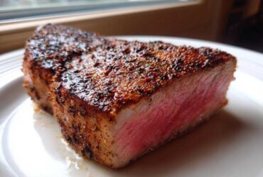 Close-up of a thick, medium-rare Blackened Tuna Steak showing a dark, seasoned crust and bright pink interior.