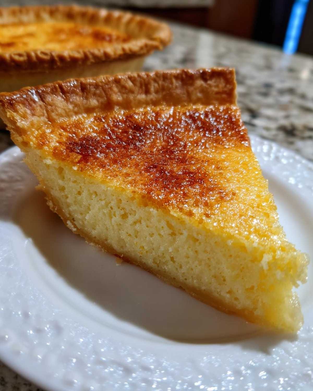 Close-up of a perfect slice of buttermilk pie showing a rich, creamy yellow filling and a golden, slightly caramelized top crust.