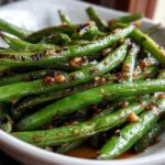 Vibrant green beans coated in a savory, dark garlic sauce, ready to serve.