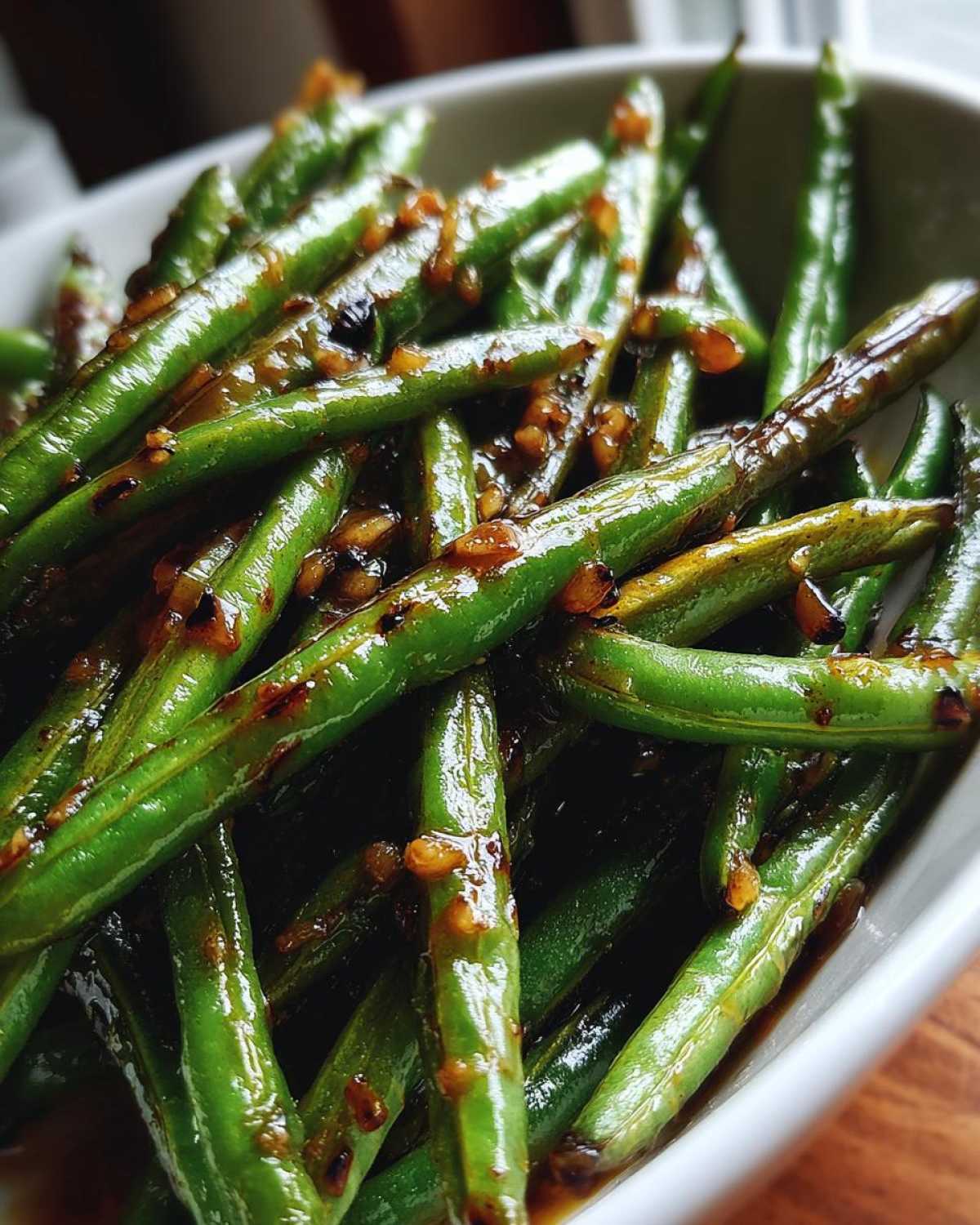 Vibrant close-up of glossy chinese green beans with garlic sauce coating the vibrant green vegetables.