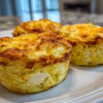 Three freshly baked cottage cheese egg cups starbucks style sitting on a white plate with golden brown tops.