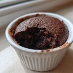A rich, dark chocolate Cottage Cheese Microwave Brownie in a white ramekin with a bite taken out.