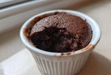 A rich, dark chocolate Cottage Cheese Microwave Brownie in a white ramekin with a bite taken out.