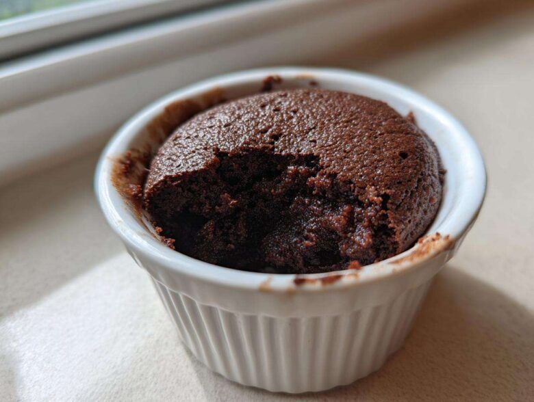 A rich, dark chocolate Cottage Cheese Microwave Brownie in a white ramekin with a bite taken out.