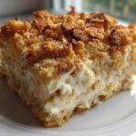 A close-up of a square serving of creamy hot chicken salad with a crunchy, golden-brown topping.