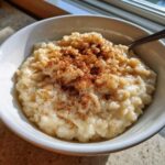 Close-up of creamy rice pudding topped generously with ground cinnamon in a white bowl.