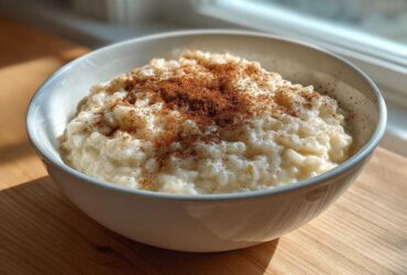 A white bowl filled with creamy rice pudding recipe, generously sprinkled with ground cinnamon.