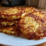 A stack of golden brown, crispy potato pancakes piled high on a white plate.