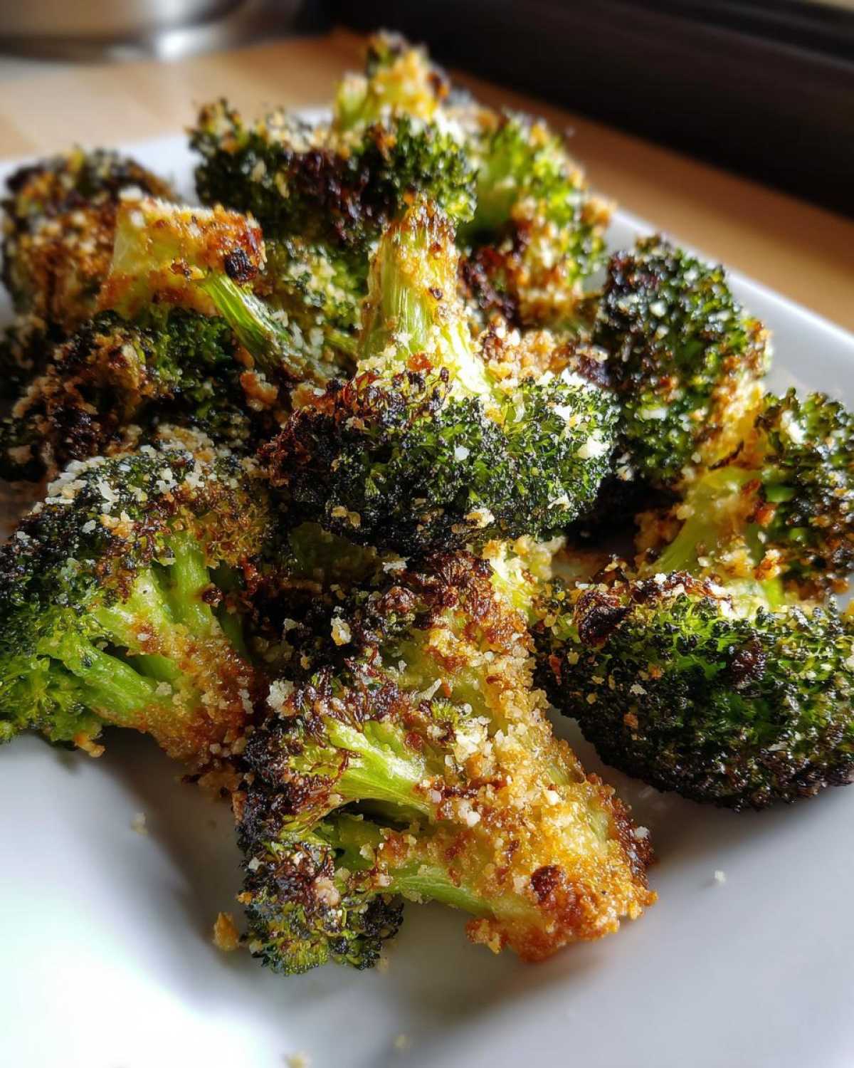Close-up of perfectly crispy roasted broccoli florets topped with golden parmesan cheese.
